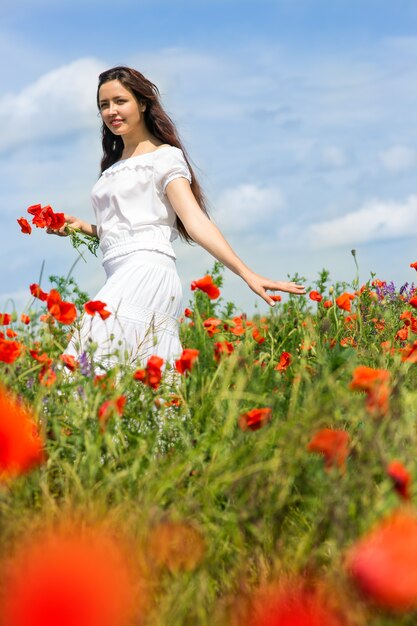 Fille marche dans un champ de coquelicots