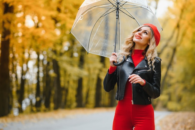 Une fille marche dans le parc d'automne sous un parapluie