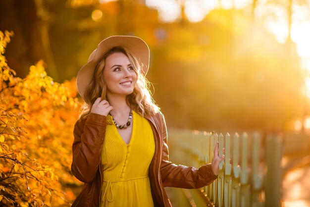 Fille marche en robe jaune dans le parc automne