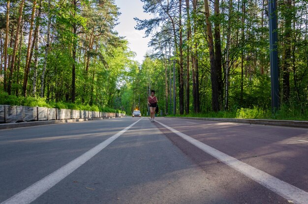 Une fille marche sur la route dans la forêt.