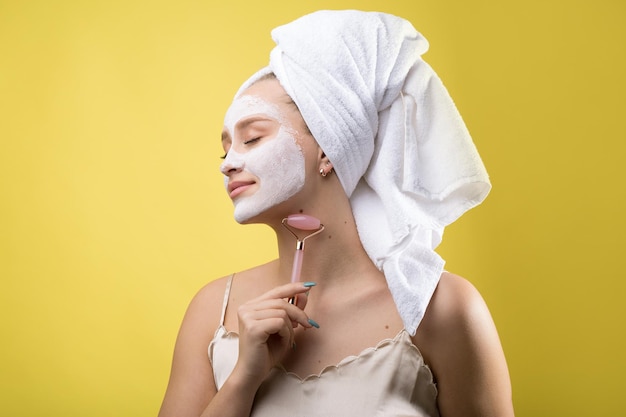 Fille avec un masque cosmétique sur son visage dans une serviette blanche.