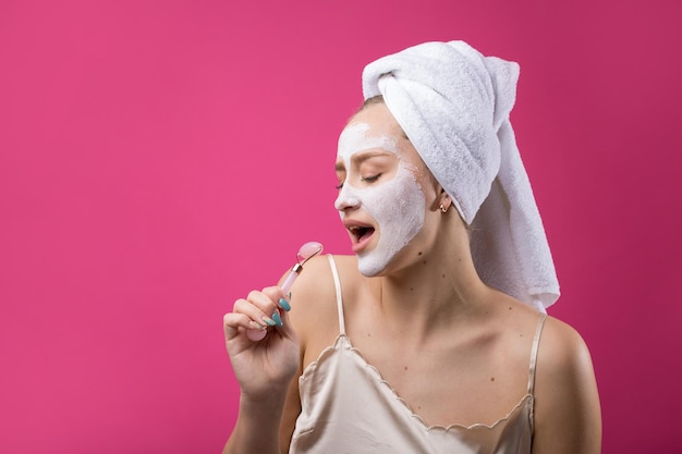 Fille avec un masque cosmétique sur son visage dans une serviette blanche.