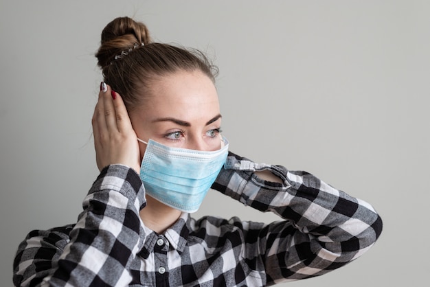 Fille avec un masque médical pour la protéger du virus. Pandémie de coronavirus. Femme avec masque debout. Les personnes hospitalisées, diagnostiquées, mettent souvent de la carantine (isolement) pour arrêter la propagation de Corona.