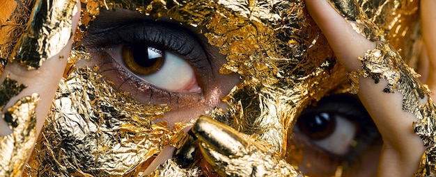 Fille avec un masque sur son visage en feuille d'or Portrait en studio sombre d'une brune sur un fond abstrait