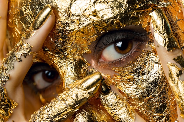 Fille avec un masque sur le visage en feuille d'or.