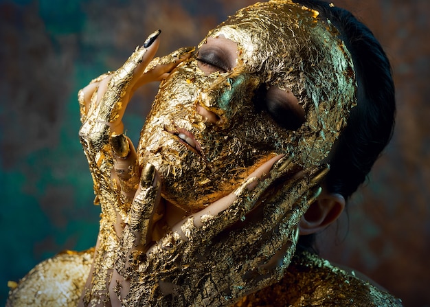 Fille avec un masque sur le visage en feuille d'or.