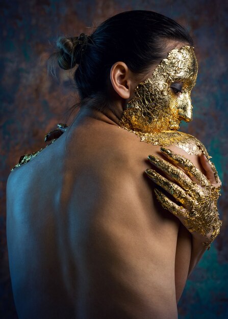 Fille avec un masque sur le visage en feuille d'or.