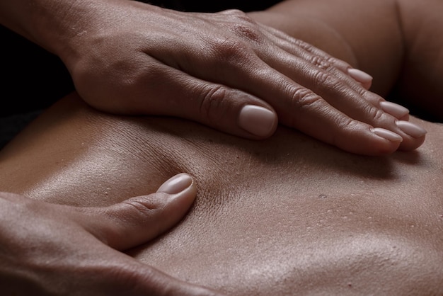 Photo fille de masseur fait un gros plan de massage sur un massage de gros plan de fond sombre