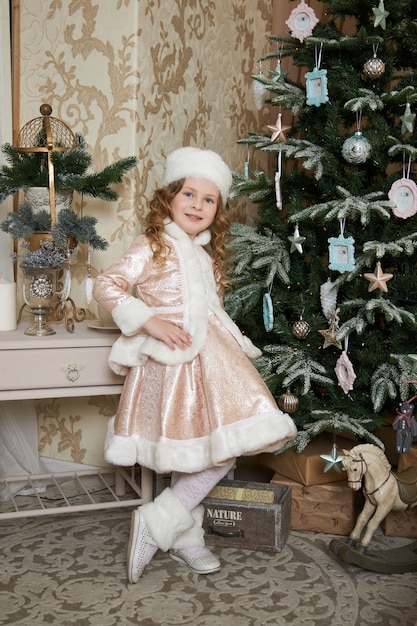 Fille et un matin de Noël, un enfant posant par arbre de Noël