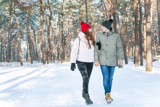 Fille et mec se promènent dans le parc d'hiver et se regardent Jeune couple dans la forêt enneigée