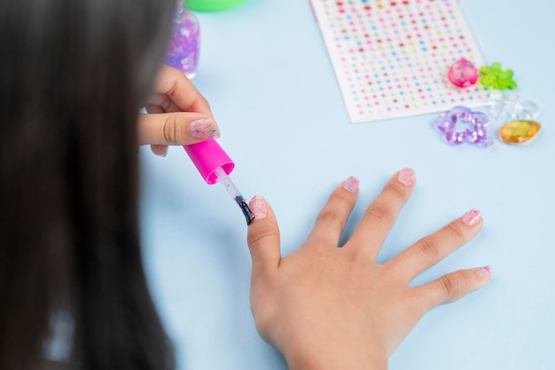 Une fille méconnaissable peint ses ongles avec du vernis à la maison