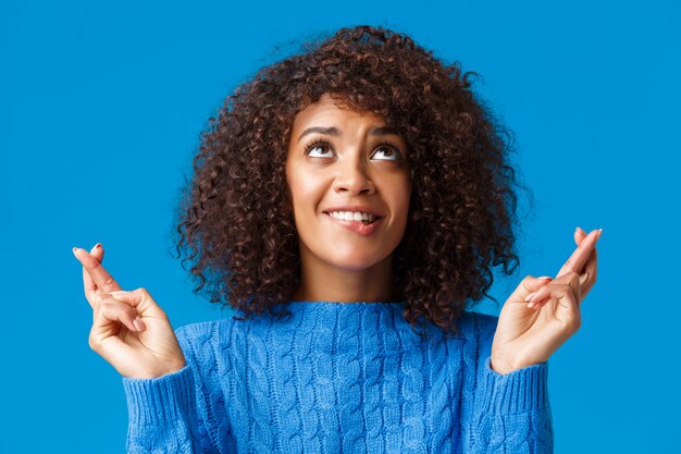 Fille mendiant Dieu son rêve devenu réalité. Mignonne et idiote femme aux cheveux bouclés afro-américaine avec coupe de cheveux afro, lèvre mordante de la tentation et du désir, croise les doigts bonne chance regarde la mendicité