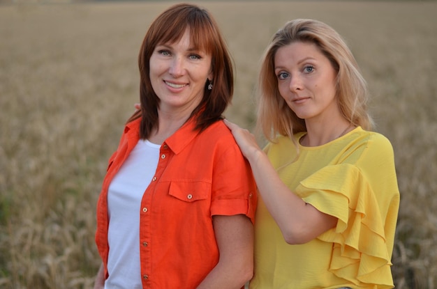 une fille et une mère dans un champ de blé sourient et parlent négligemment