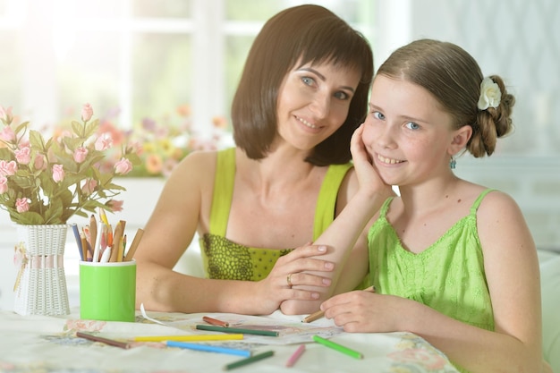 Fille avec mère dessinant à la table à la maison