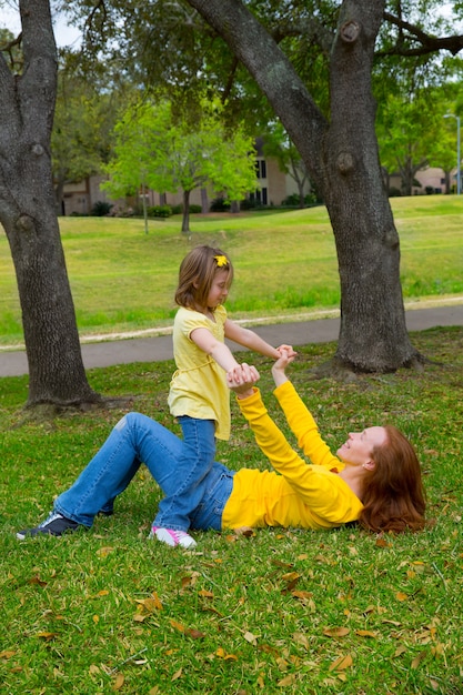 Fille et mère jouant allongé sur la pelouse du parc