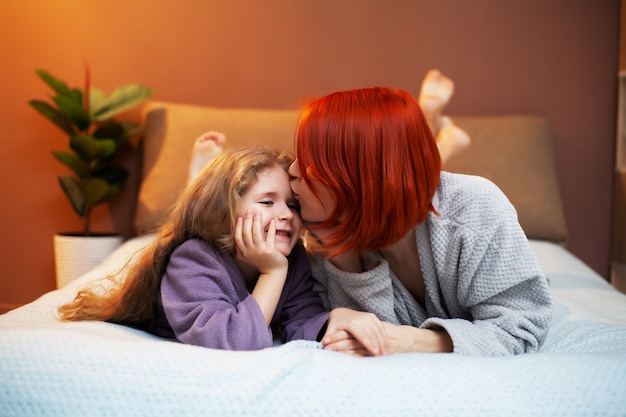 Fille et mère jouant sur le lit dans la pépinière