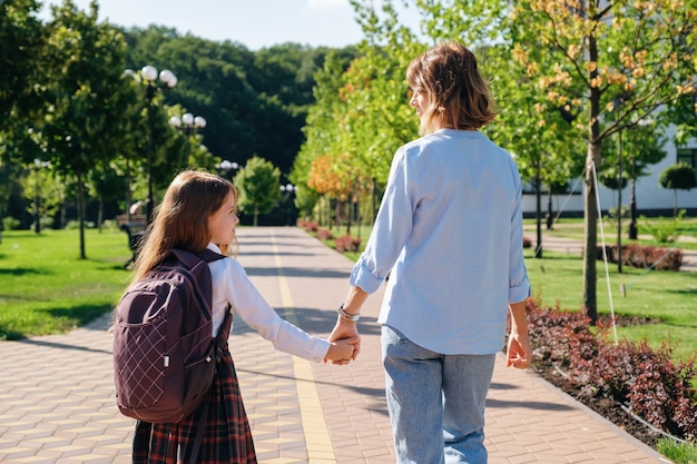 Fille et mère marchant ensemble à l'école en bas de la rue