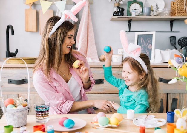 Photo fille et mère en oreilles de lapin s'amusant avec des oeufs de pâques