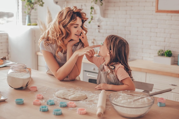 Fille et mère passent du temps ensemble dans la cuisine et se mettent de la farine sur le nez