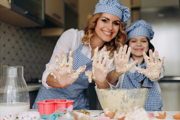 Fille et mère remuent la pâte et montrent les bras sales