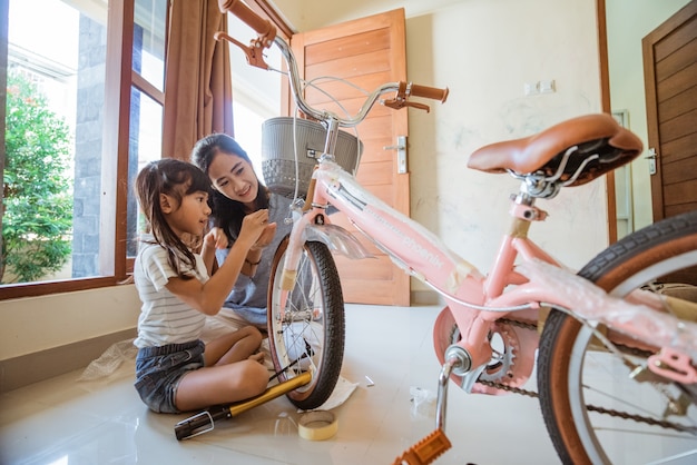La fille et la mère s'amusent à installer leur nouveau panier de vélo
