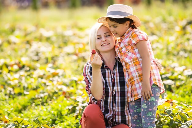 fille et mère travaille dans le potager, fraises récoltées