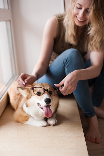 Fille met des lunettes sur un chien. Chiot Welsh Corgi Pembroke drôle avec des lunettes