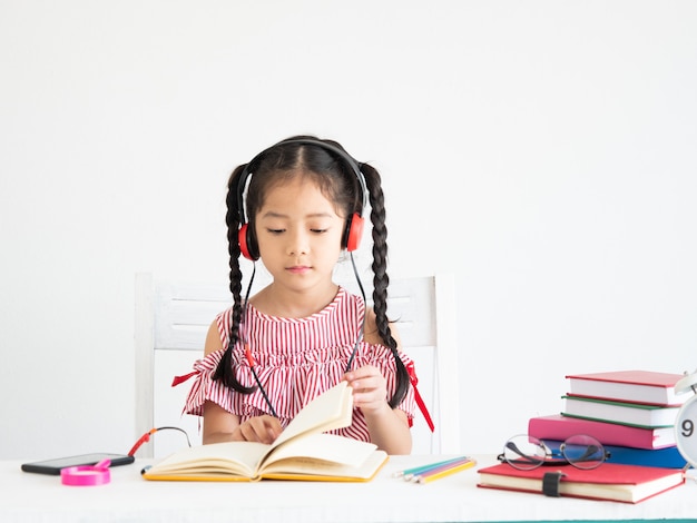 Fille mignonne asiatique avec un livre sur le bureau