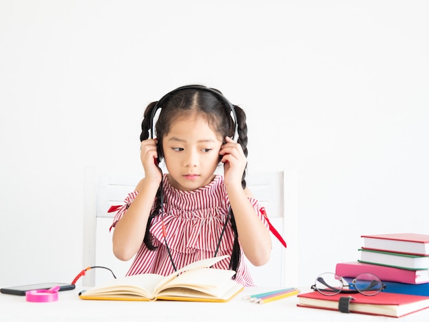 Fille mignonne asiatique avec un livre sur le bureau