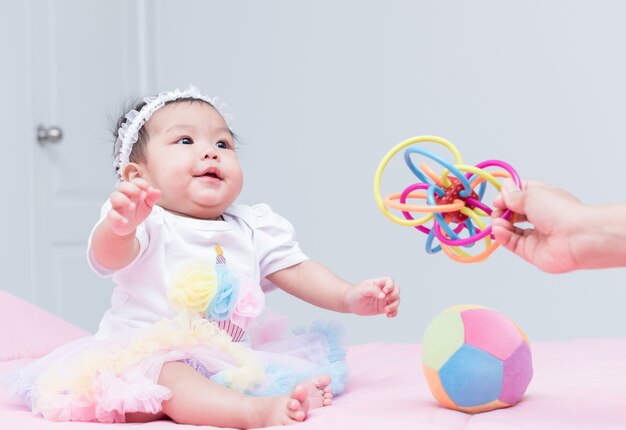 fille mignonne bébé sourire et jouer jouet avec la main de la mère