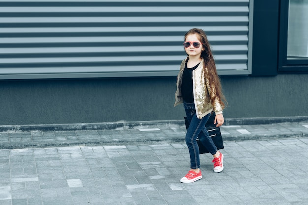 Fille mignonne élégante avec un sac en papier noir qui revient des achats