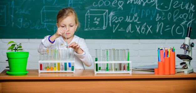 Fille mignonne élève jouer avec des tubes à essai et des liquides colorés Expérience chimique scolaire Éducation scolaire Approche intéressante pour apprendre L'enfant aime expérimenter Explorer et enquêter Leçon scolaire