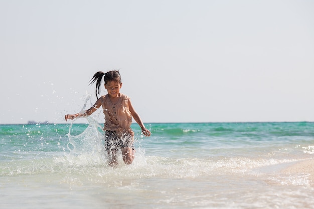 Fille mignonne enfant asiatique s&#39;amuser à jouer et courir sur la plage près de la mer magnifique en vacances d&#39;été