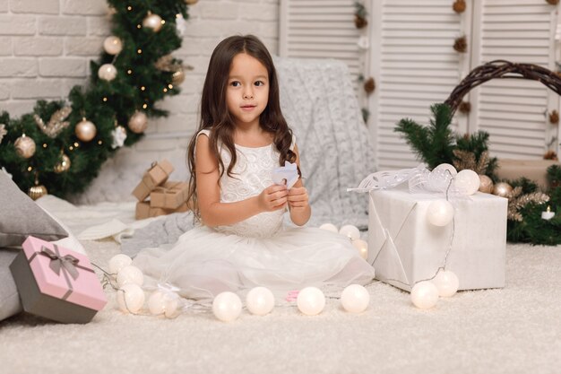 Fille mignonne enfant fait des flocons de neige en papier pour la décoration de l'arbre de Noël à la maison