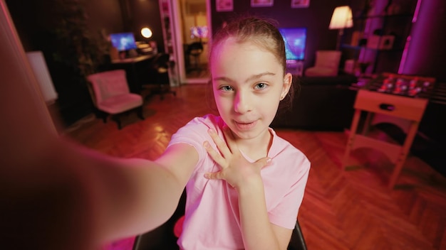 Une fille mignonne enseigne à sa mère comment faire des vidéos virales en ligne pour les médias sociaux dans le style POV Maman apprend à faire des clips tendance de la fille d'un influenceur à la maison éclairée par du néon rose