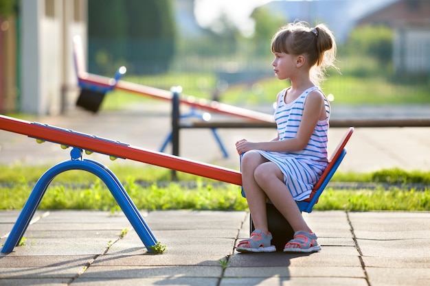 Fille mignonne jeune enfant à l'extérieur sur la balançoire en balançoire sur une journée d'été ensoleillée.