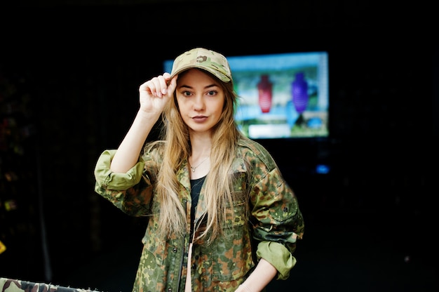 Fille militaire en uniforme de camouflage sur le fond de l'armée sur le champ de tir.