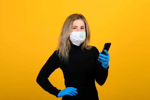 Une fille mince dans un body noir et un masque médical de virus pose