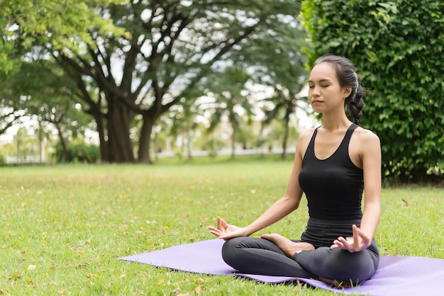 Fille mince jouer au yoga sur la pelouse au parkrelax in nutureLes filles asiatiques aiment la santé en pratiquant le yoga