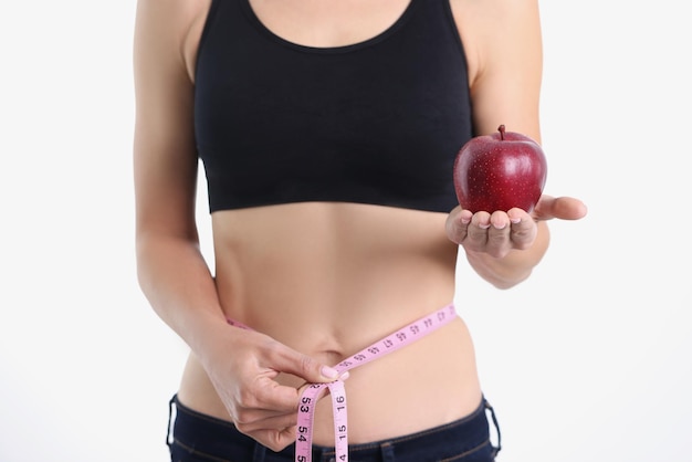 Une fille mince montre une pomme et un ruban à mesurer autour de l'alimentation de la taille et du concept de corps mince