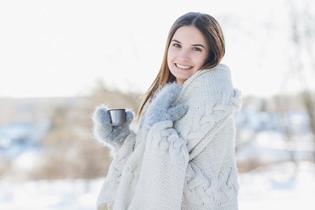 Fille en mitaines et une couverture buvant du thé chaud