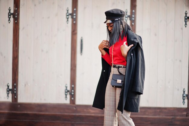 Fille de mode afro-américaine en manteau et casquette de gavroche posée dans la rue