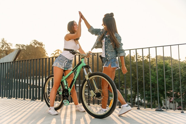 Une fille à la mode des années 30 avec vélo en attente de sa copine chaude en short tentant sur la terrasse d'observation spécialement équipée