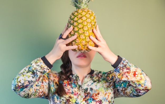 Fille de mode tenant l'ananas devant le visage