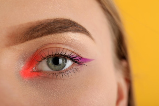 Fille modèle avec du maquillage sur fond jaune, gros plan