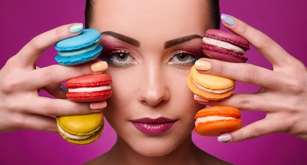 Fille de modèle de mode beauté glamour avec maquillage coloré et macarons.