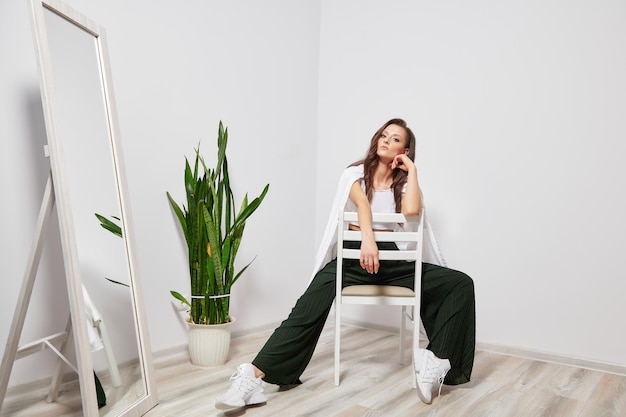 Fille moderne et élégante assise sur une chaise et posant