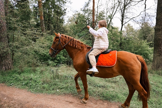 Une fille monte à cheval à l'automne dans la forêt