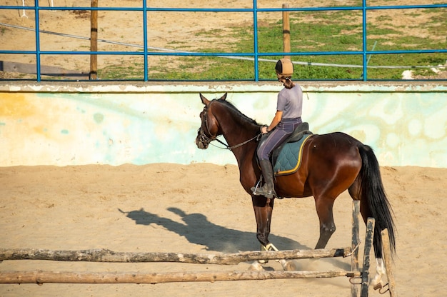 La fille monte un cheval sur l'hippodrome