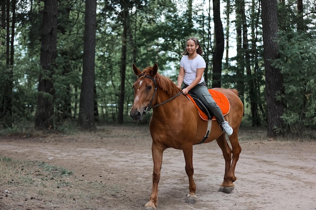 Une fille monte à cheval pendant l'été chaud dans la forêt